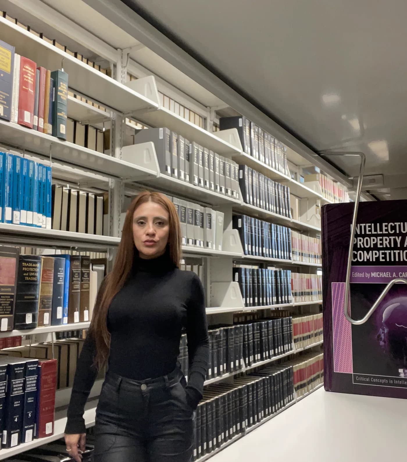 Daniella Hernández beside the intellectual property section of a law library.